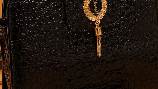 Black handbag with gold accents on a wooden surface