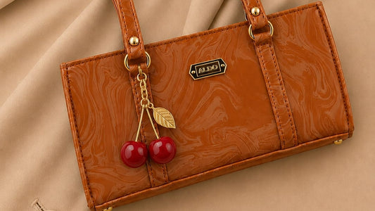 Brown handbag with cherry charm on a beige fabric background