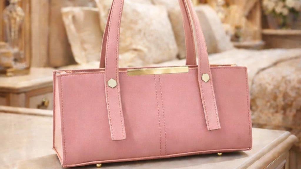 Pink handbag on a surface with a blurred background of a room.