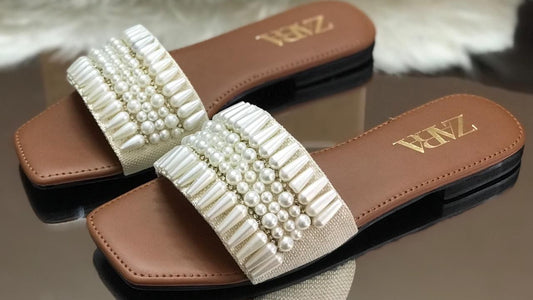 Pair of brown and beige embellished sandals with 'Zara' branding on a reflective surface.