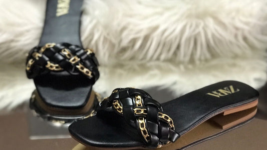Black sandals with gold chain details on a Zara branded box with fur background