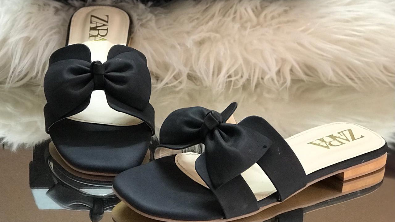 Zara sandals with black bows on a fluffy white surface next to a Zara box.