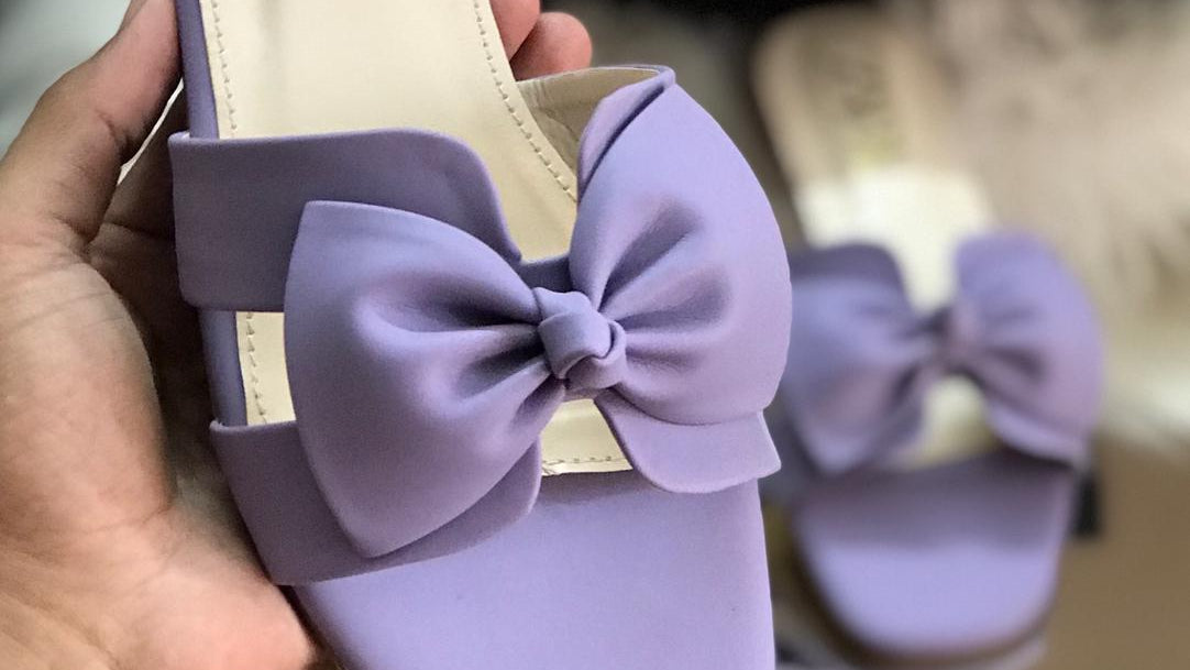 Purple slide sandal with a bow held by a hand, Zara bag in the background
