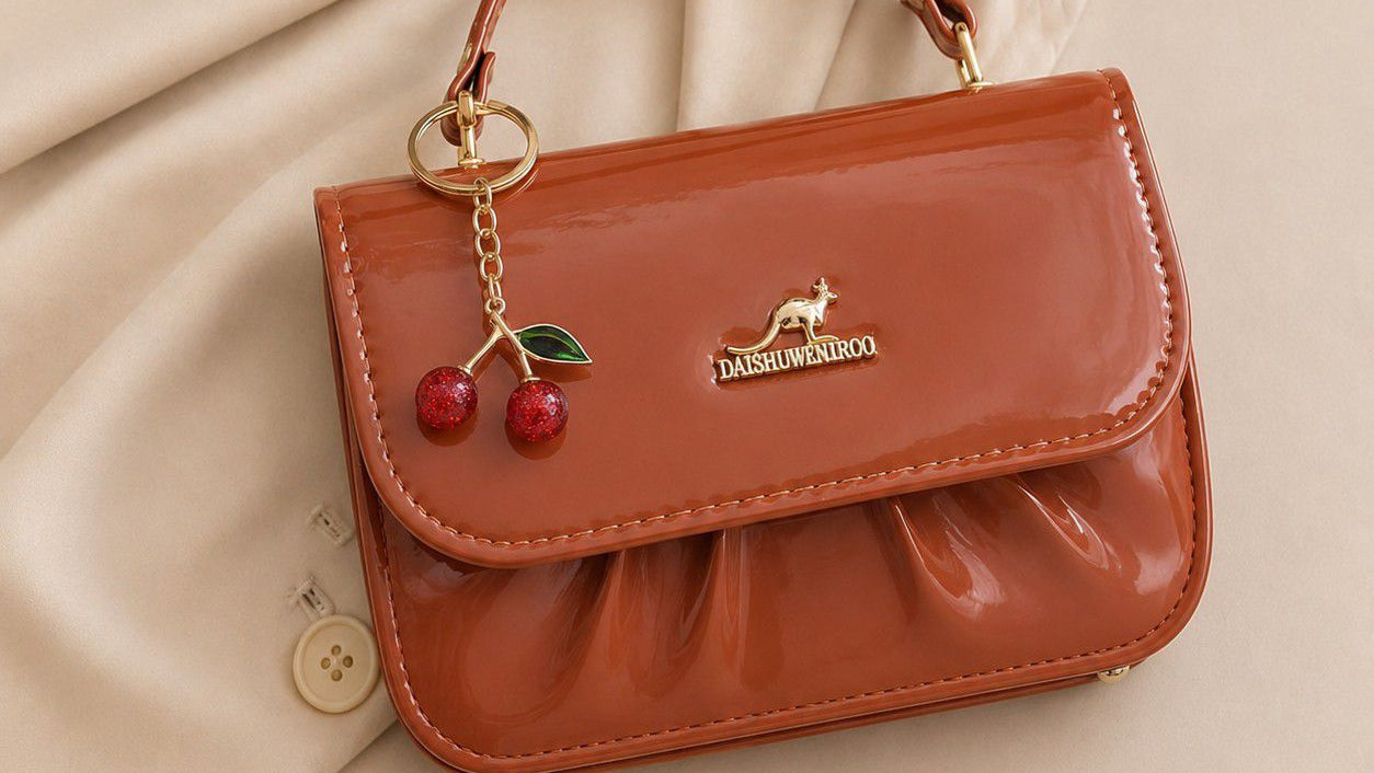 Brown handbag with cherry charm on a beige fabric background