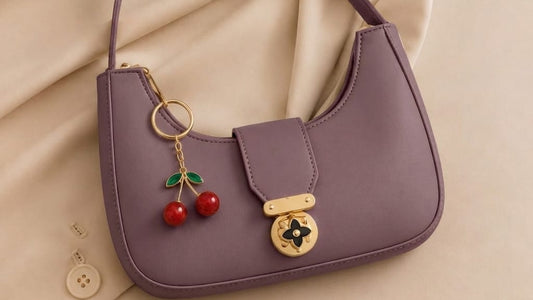 Purple handbag with cherry charm on a beige fabric background