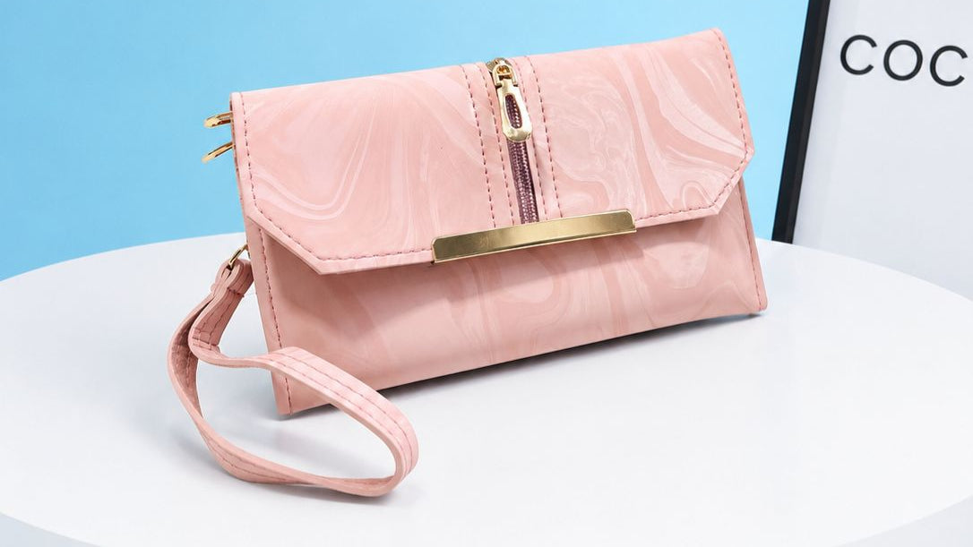 Pink handbag with gold accents on a white surface with a light blue background