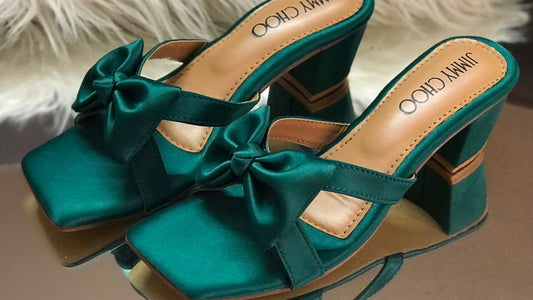 Teal high-heeled shoes with bows on a white fur surface