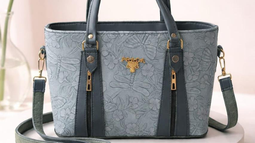 Blue handbag with gold accents on a white platform
