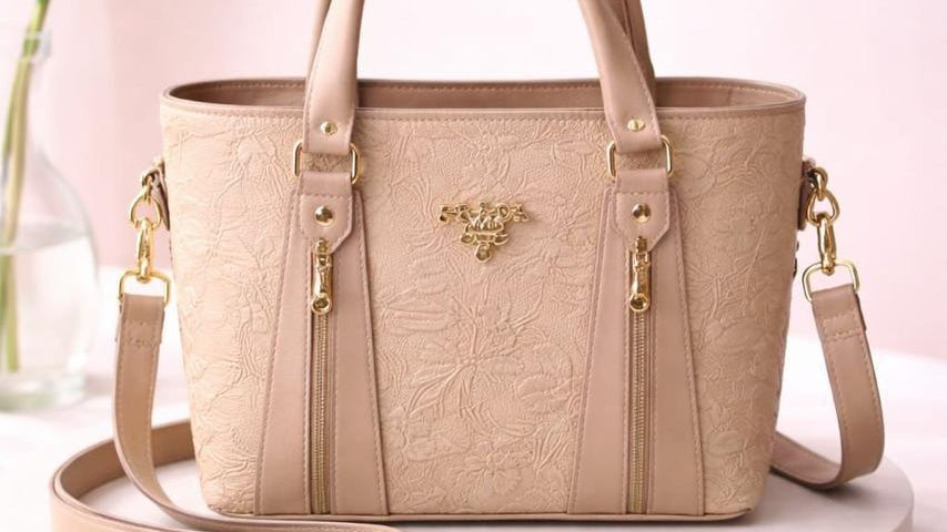 Beige handbag with gold accents on a white pedestal