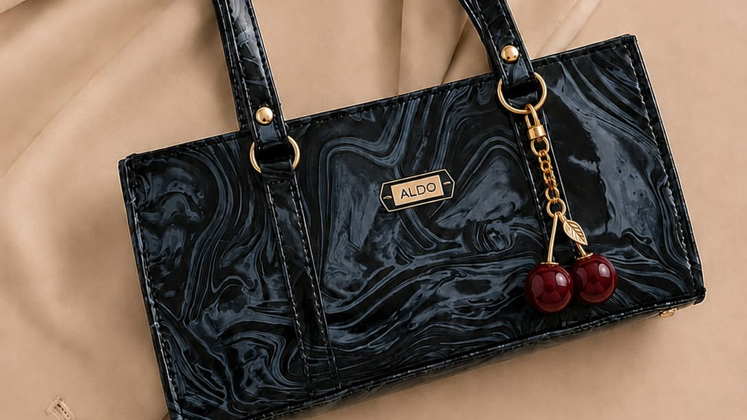 Black marbled handbag with cherry charm on a beige fabric background