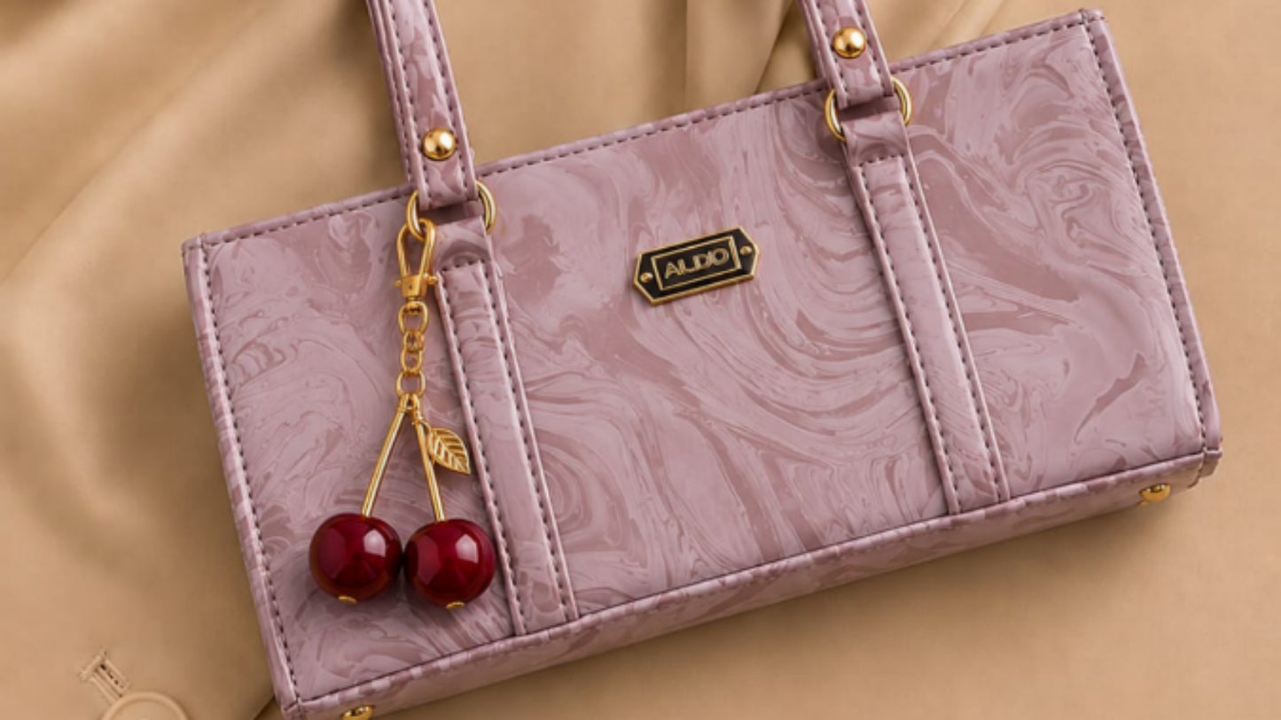 Purple handbag with cherry decorations on a beige fabric background