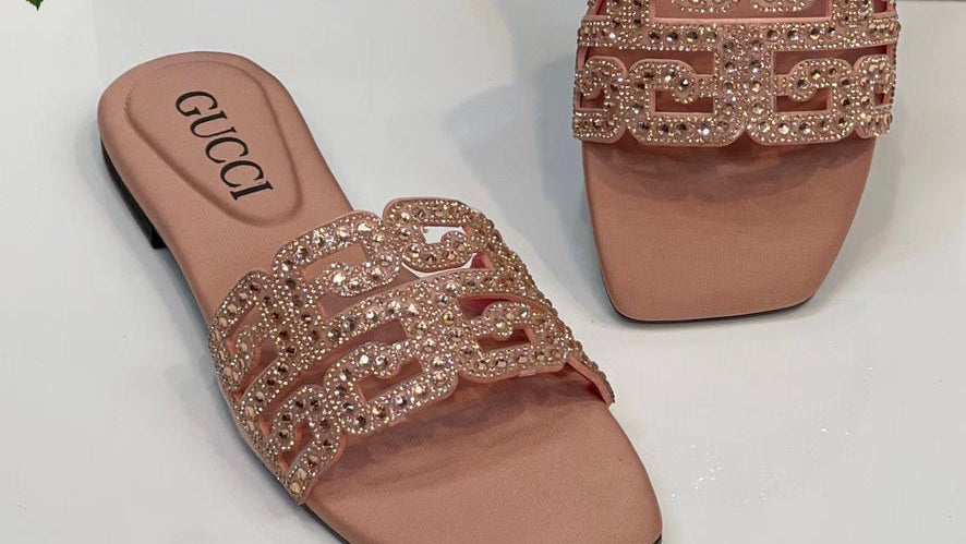 Pair of Gucci sandals with embellishments in front of a Gucci box.