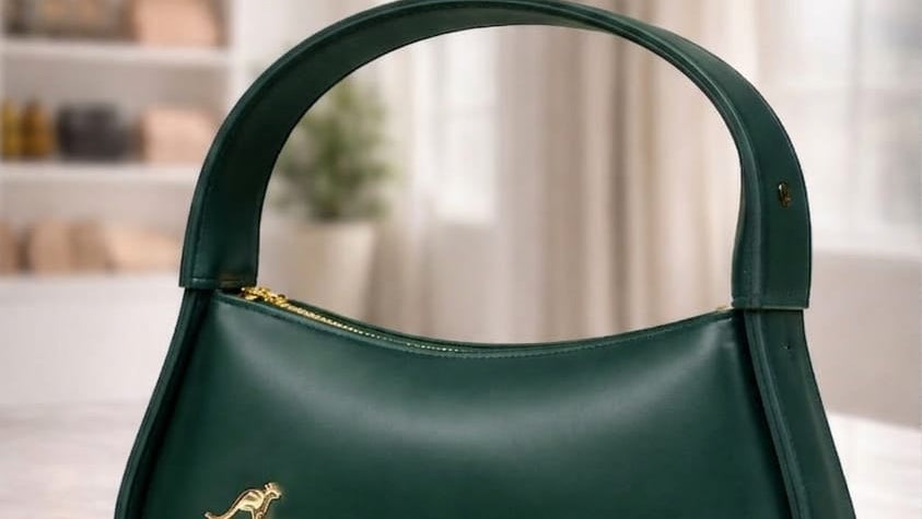 Green handbag with gold accents on a light surface