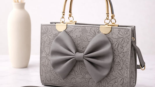 Gray handbag with a large bow on a white surface