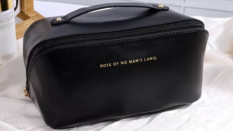 Black cosmetic bag with 'Rose of No Man's Land' branding on a white surface.