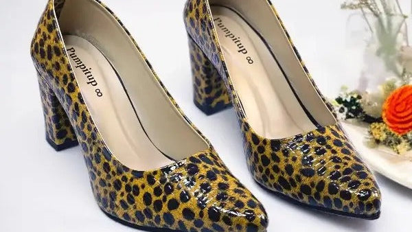 Leopard print high-heeled shoes on a white surface with decorative elements.