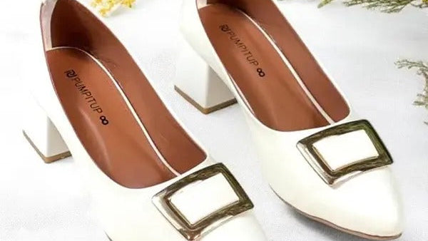 Pair of white high-heeled shoes with brown accents on a light background